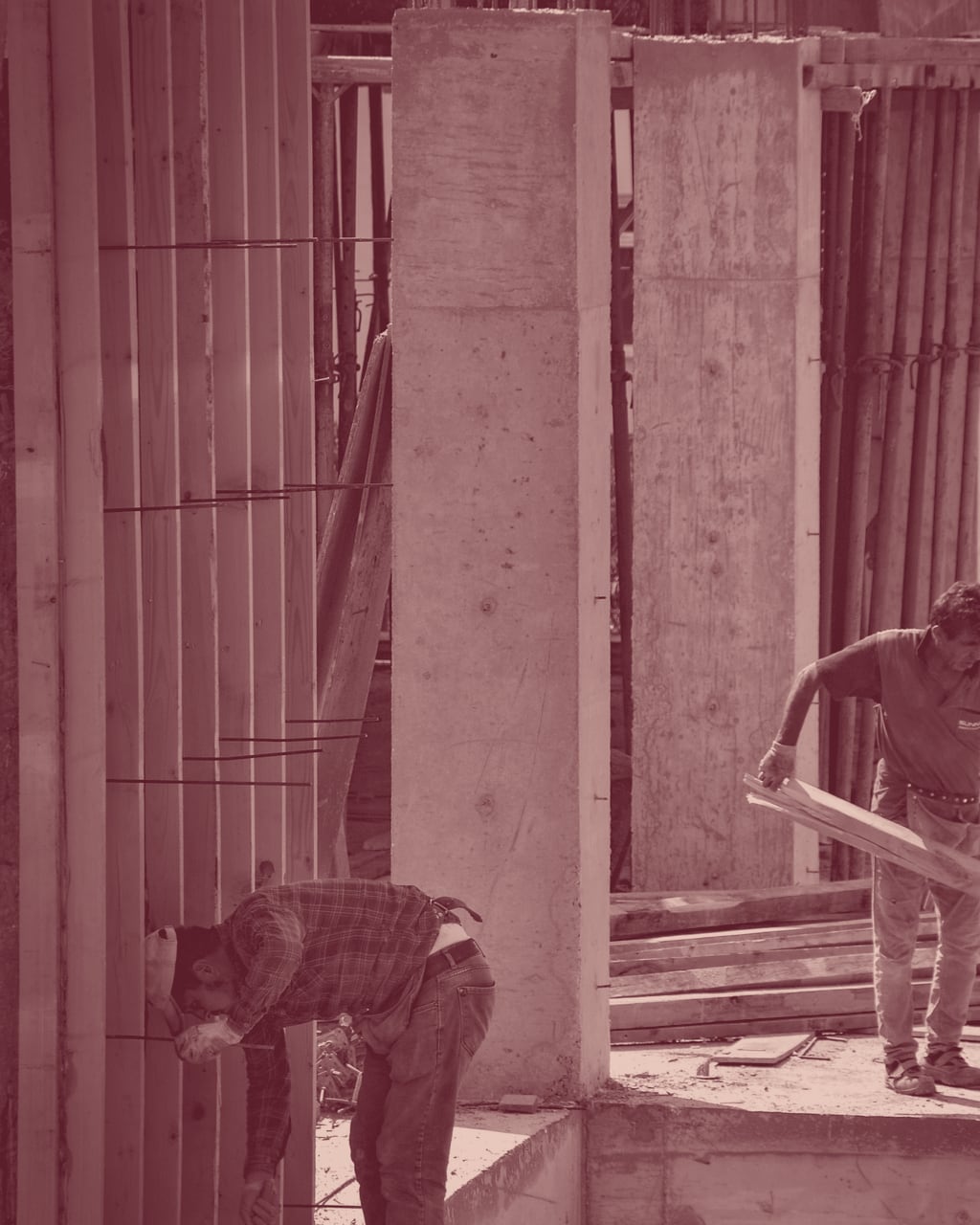 Un chantier de gros œuvre, poteaux et coffrages de béton, deux compagnons au travail