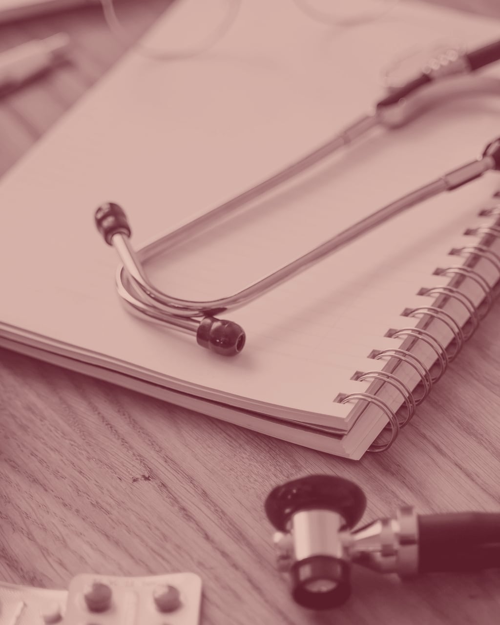 Un stéthoscope posé sur un carnet de notes, à côté d'une plaquette de comprimés